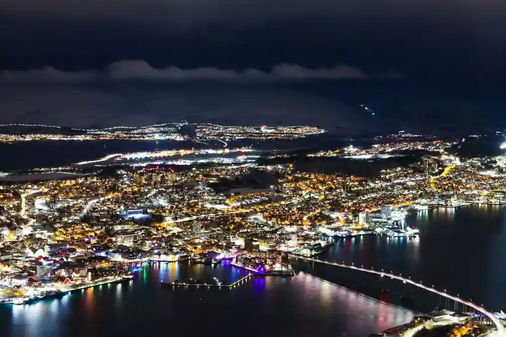 Tromsø havnefront med opplyste gater og snøkledde fjell