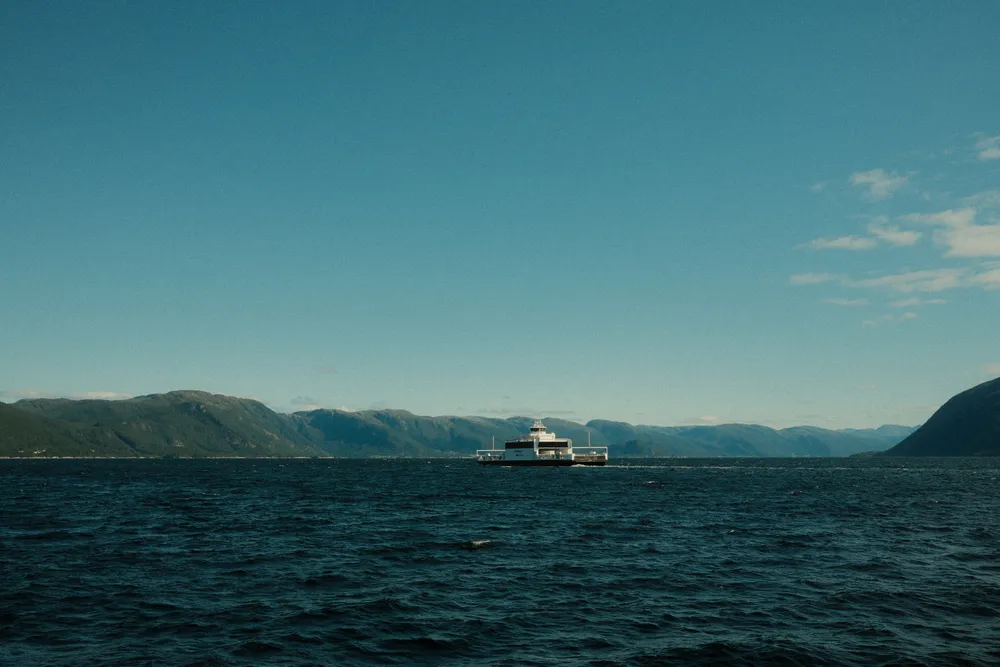 Ferge på norsk fjord under klar himmel