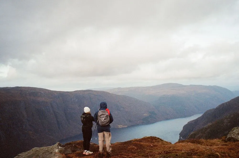 To turgåere nyter storslått utsikt over norsk fjord og ville fjell