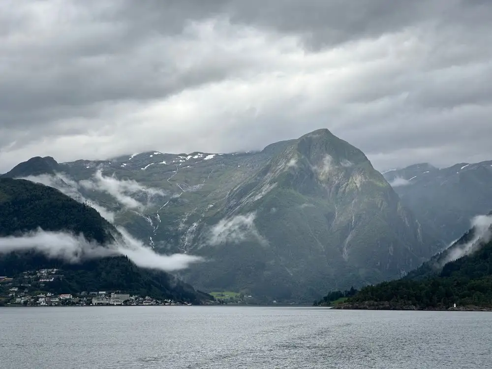 Dramatisk vestnorsk fjordlandskap med fjelltopper og blikkstille vann